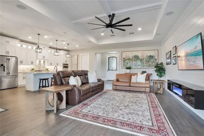 Spacious open-concept great room with luxury vinyl plank flooring, tray ceiling, and seamless flow to the kitchen and outdoor living areas.