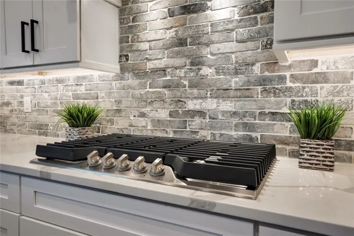 Natural gas cooktop with custom tile backsplash, premium finishes, and modern design details ideal for everyday cooking and entertaining.