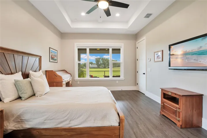 Private owner's suite featuring tray ceilings, luxury flooring, and tranquil views of the golf course and surrounding landscape.