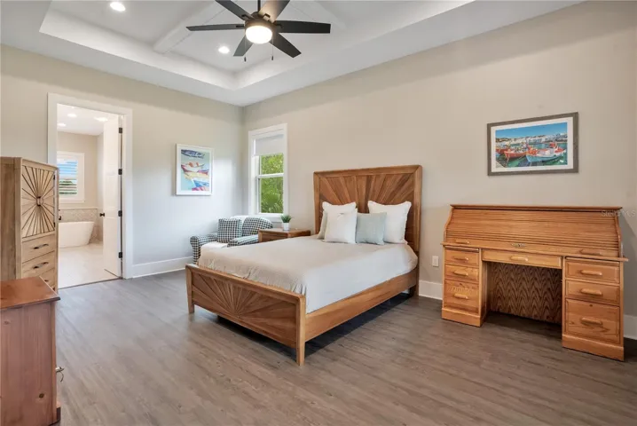 Private primary suite featuring tray ceilings, luxury vinyl plank flooring, and generous space for a sitting area or additional furnishings.