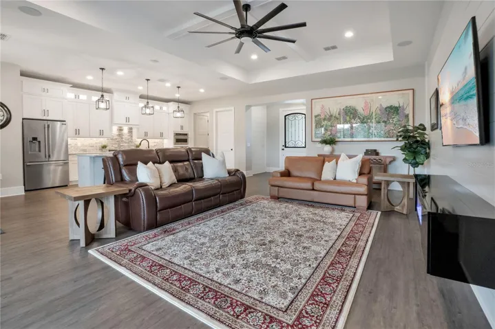 Spacious family room with elegant tray ceiling, designer lighting, and a comfortable layout ideal for relaxing or hosting guests.