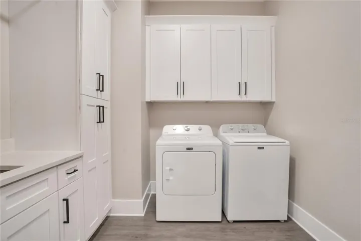 Spacious laundry room featuring upper cabinetry, utility workspace, and additional storage to simplify household tasks.