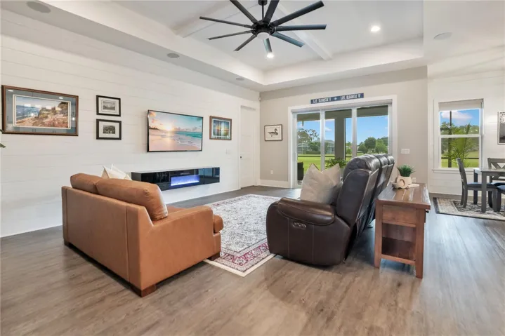 Comfortable living space with expansive windows showcasing natural light and picturesque views of the surrounding golf course community.
