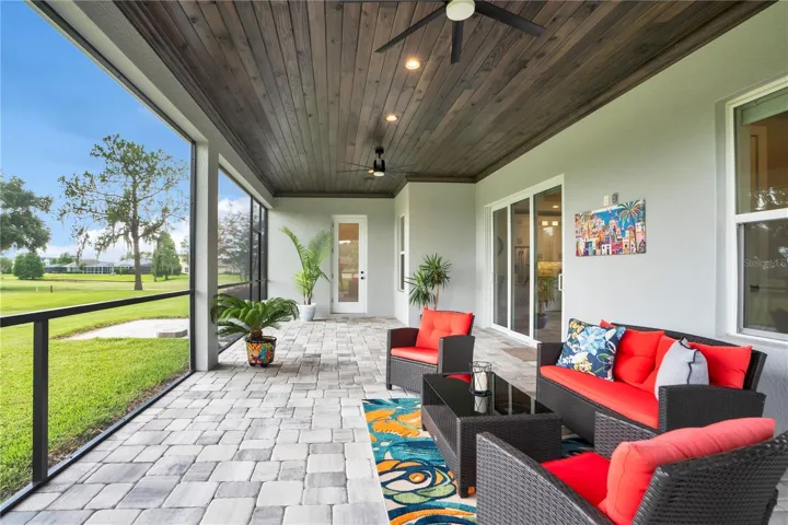 Covered screened lanai with tongue-and-groove ceiling overlooking the backyard and golf course, creating the perfect indoor-outdoor living space.