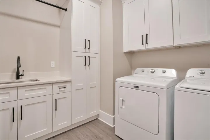 Well-equipped laundry room featuring built-in cabinetry, additional storage, utility sink, and functional workspace for everyday convenience.