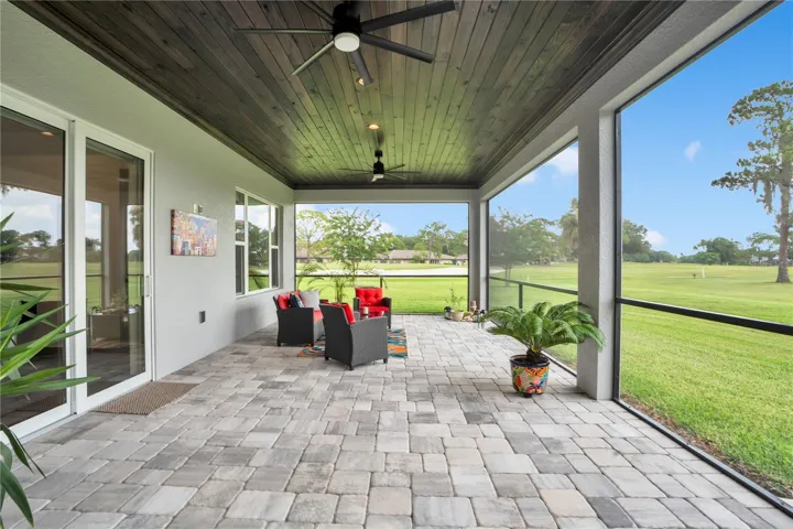 Covered screened lanai with paver flooring, tongue-and-groove ceiling, and panoramic views of the golf course and surrounding greenspace.