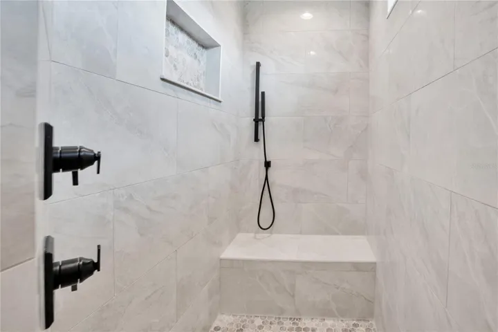 Luxury walk-in shower with floor-to-ceiling tile, frameless glass enclosure, and modern fixtures creating a spa-inspired primary bathroom retreat.