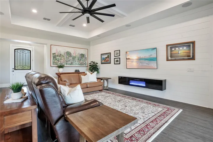 Expansive great room with tray ceiling, luxury vinyl plank flooring, and an open-concept design that connects seamlessly to the kitchen and dining areas.