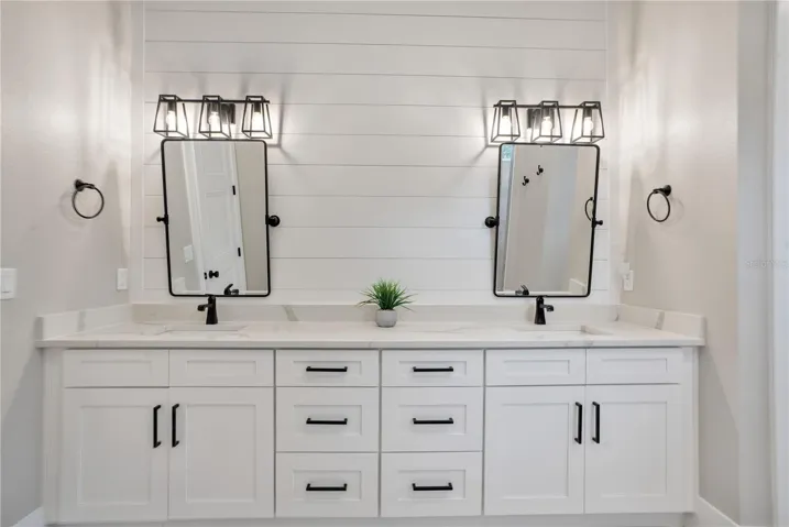 Luxurious primary bathroom featuring dual vanities, quartz countertops, designer lighting, and abundant storage for everyday convenience.
