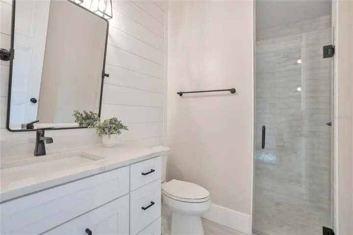 En suite well-appointed secondary bathroom with walk-in shower, modern vanity, and bright, neutral finishes.