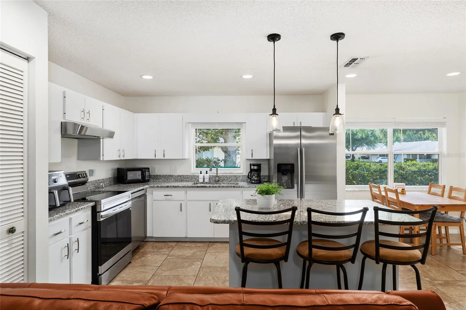Eat-in kitchen featuring granite countertops, stainless steel appliances, a kitchen island with bar seating, a breakfast area, and additional seating.