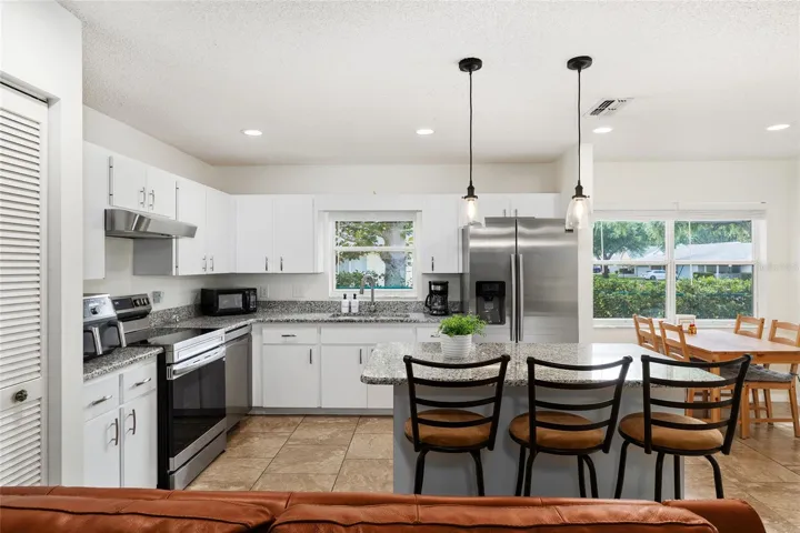 Eat-in kitchen featuring granite countertops, stainless steel appliances, a kitchen island with bar seating, a breakfast area, and additional seating.