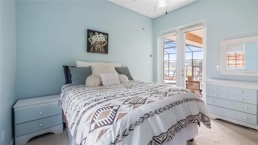 Bedroom 2, doorway to hall/guest bathroom and double glass doors to rear patio and pool