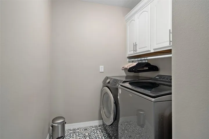laundry room upstairs with custom tile, cabinetry and clothes rack.
