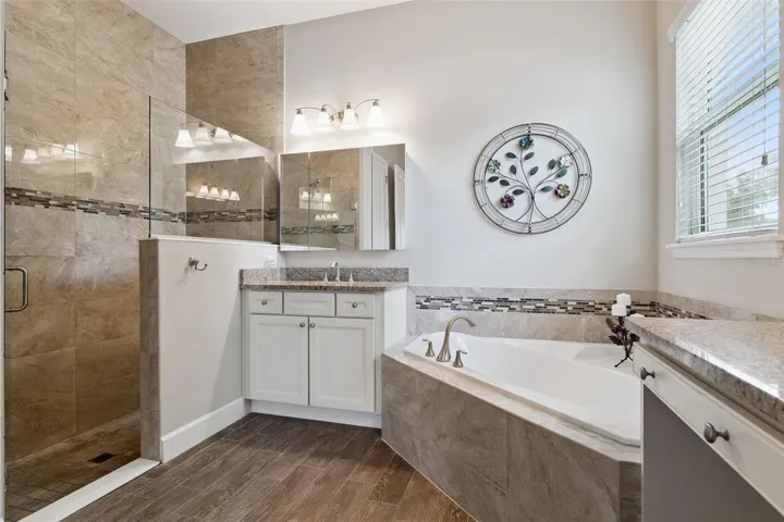 12' x 11' Primary Bath w/ separate vanities, glass enclosed walk-in shower w/ bench seat & corner soaking tub