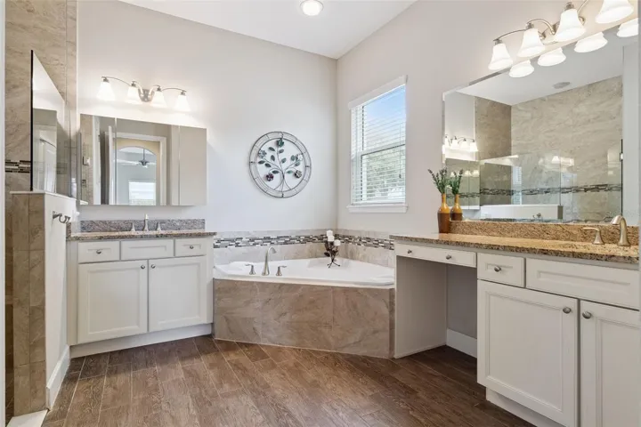 12' x 11' Primary Bath w/ separate vanities, glass enclosed walk-in shower w/ bench seat & corner soaking tub