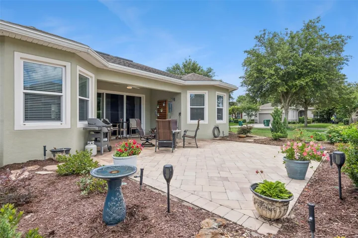 View of stone paver lanai & lush landscaping on a corner homesite