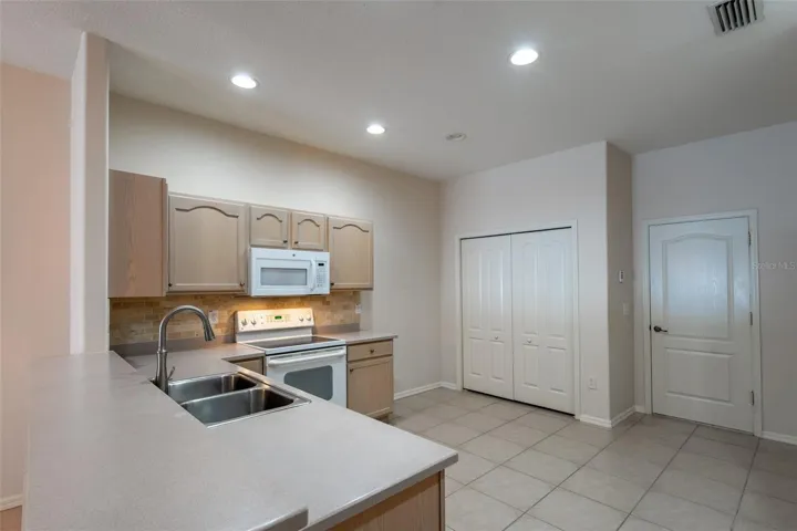 Kitchen view of Range/Microwave, Closet Pantry and door to Garage