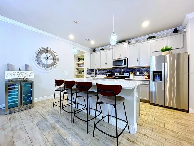 The stunning kitchen is both functional and beautiful, featuring quartz countertops, upgraded cabinetry, stainless steel appliances, a striking glass tile backsplash, and a large island perfect for gathering with family and friends.