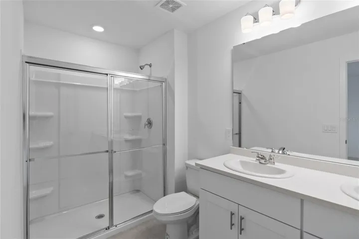 Primary Bathroom with large shower, double vanity with Quartz counters and recessed lighting.