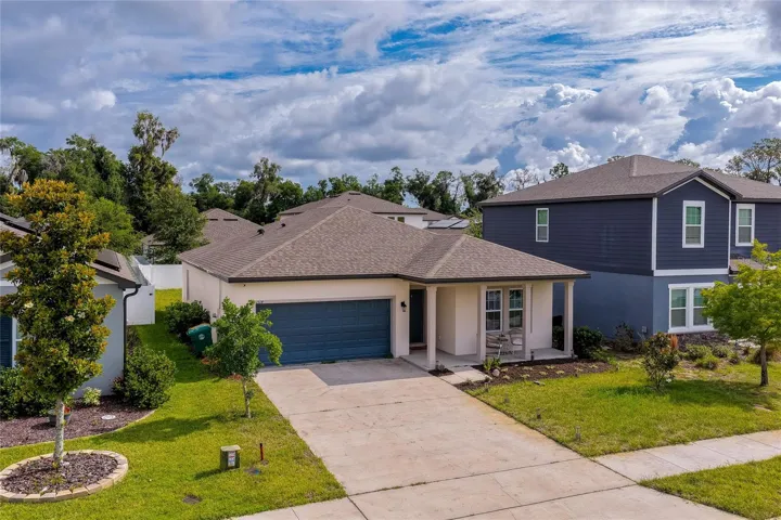 Elevated perspective of a contemporary single-family home showcasing a pristine concrete driveway, a two-car garage, and a welcoming front porch accent.