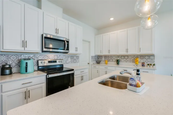 Detailed view of the kitchen's preparation area, highlighting the intricate gray and white patterned tile backsplash and under-cabinet clearance.