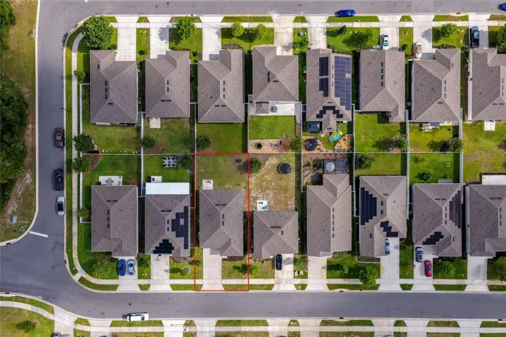 A birds-eye top-down aerial view detailing the layout of the property, outlined clearly in red to show lot boundaries, roof structure, and driveway alignment. The surrounding suburban grid illustrates the master-planned design of the community.
