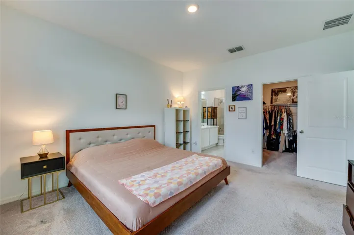 Alternative view of the expansive primary suite highlighting the open doorway to the master bathroom and a secondary entrance leading into a generous walk-in closet.