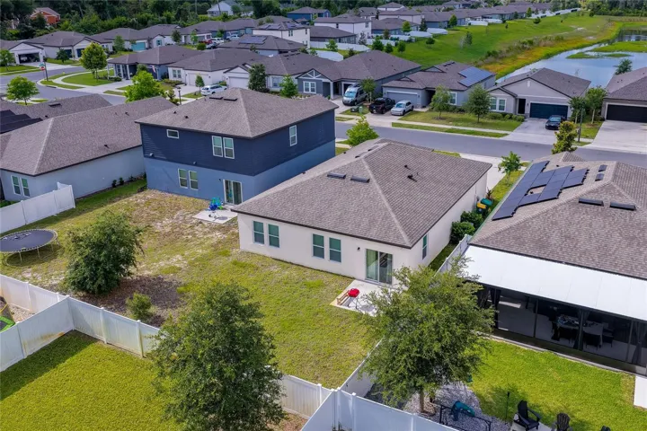 Wide high-angle shot showcasing the generous dimensions of the backyard and its integration within the neighborhood. The property backs up to expansive green spaces.