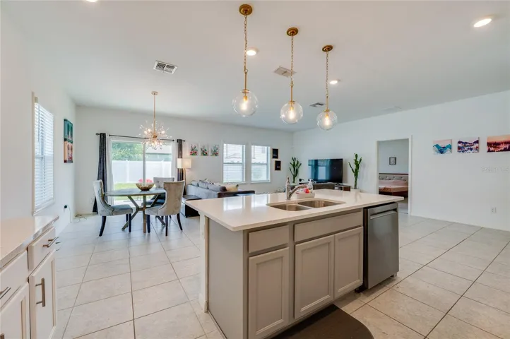 A wide perspective from behind the kitchen island looking across the entire main living area, showcasing the expansive, airy feel of the home's open layout.