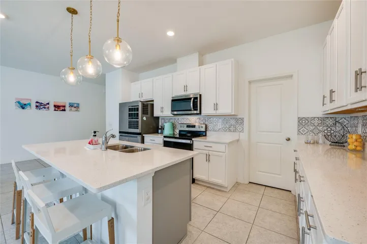 Alternate angle of the kitchen highlighting the built-in microwave, flat-top range, and a nearby interior door leading to a pantry. The layout provides plenty of counter space for meal preparation.
