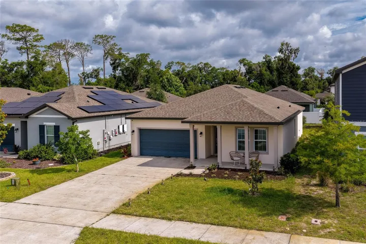 Angled aerial view highlighting the home’s architectural design, complete with a classic gabled roofline and an expansive front yard. The view also captures neighboring properties, emphasizing the community's clean and cohesive streetscape.