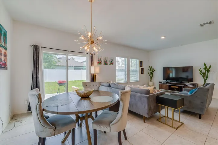 Dedicated dining nook situated next to a sliding glass door that opens directly to the backyard. A striking starburst chandelier serves as a focal point for the space.