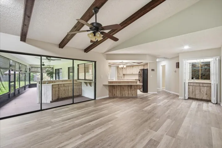 Impressive family room with soaring ceilings with stone fireplace, beams and triple sliding glass doors