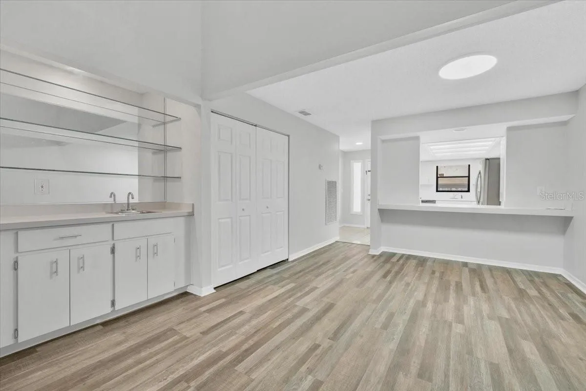 Looking back toward the entryway at the wet bar area and the kitchen pass through on the right with new flooring and paint