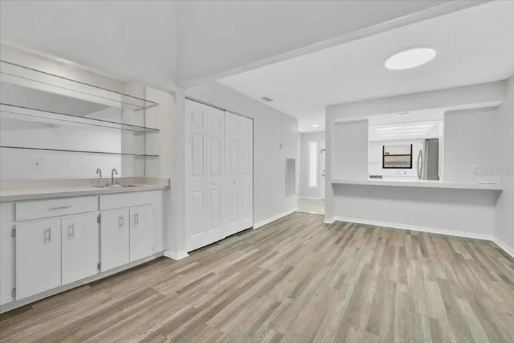 Looking back toward the entryway at the wet bar area and the kitchen pass through on the right with new flooring and paint