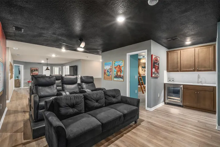 theatre room upstairs with beverage fridge and built in wet bar.