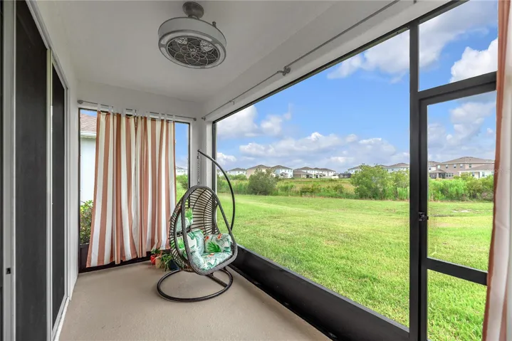 The covered and screened lanai with fan looks out over a green space, creating the perfect outdoor retreat for relaxing, entertaining, or spending quality time with family and pets