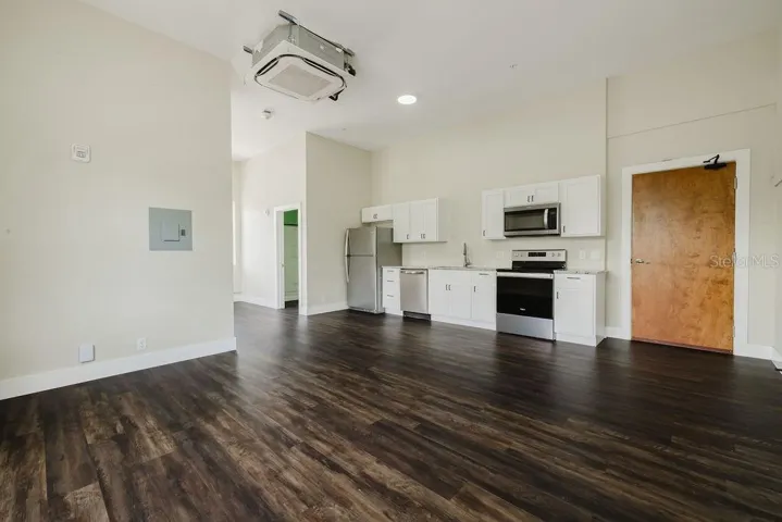 Living room area with view of kitchen and front door.