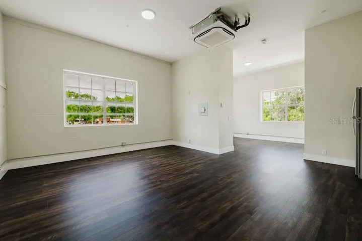 View from front door of living room with oversized windows and dividing wall to bedroom.