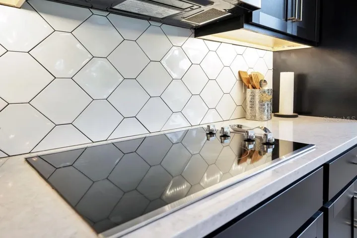 The GOURMET KITCHEN is a true showstopper, featuring BUILT-IN DOUBLE OVENS, a cooktop, stone countertops, a stylish tile backsplash, stainless steel appliances, a closet pantry, and a large island with a FARMHOUSE SINK and breakfast bar seating.