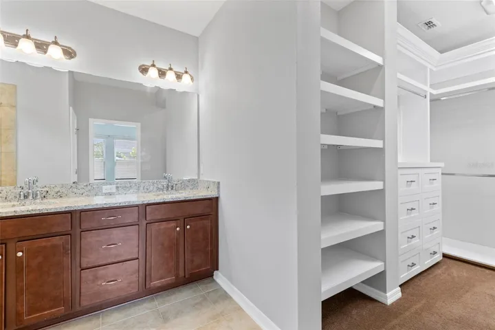Primary Bathroom - walk in closet with custom cabinets & shelving features new LED lighting on dimmer switch