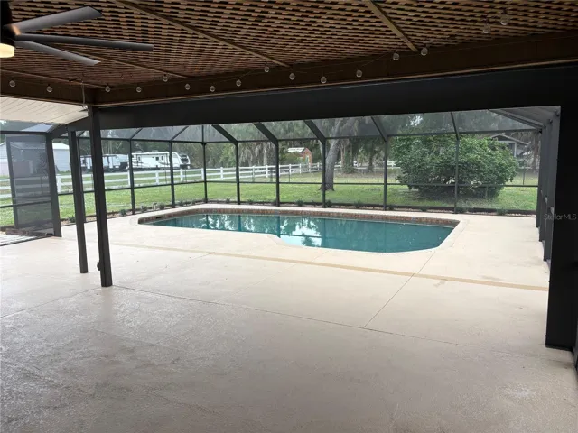 covered lanai leading to inground swimming pool