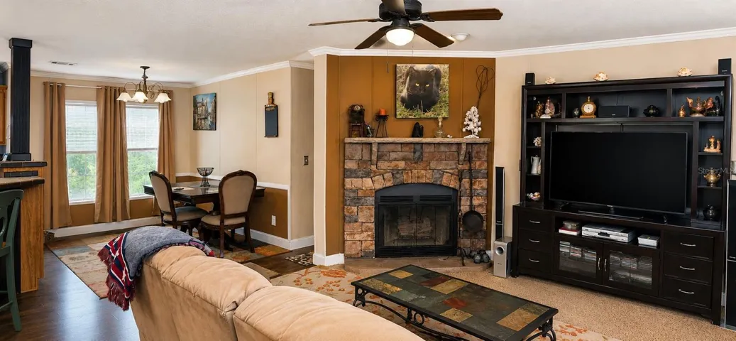 Open-concept living room featuring a stunning stone fireplace and wooded views.