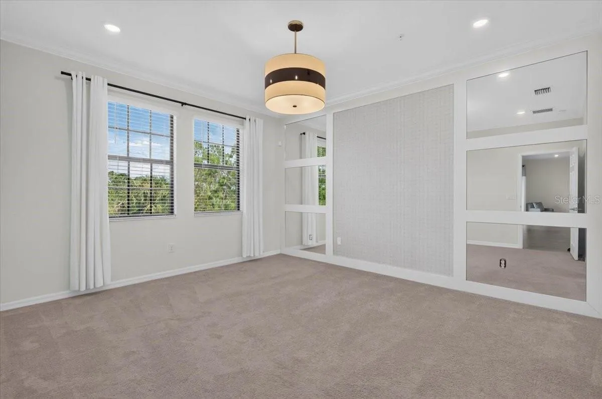 Primary Bedroom with accent wall, light fixture and window treatments