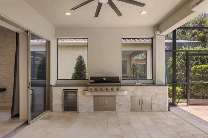 Outdoor kitchen complete with refrigerator, grill, sink, and storage