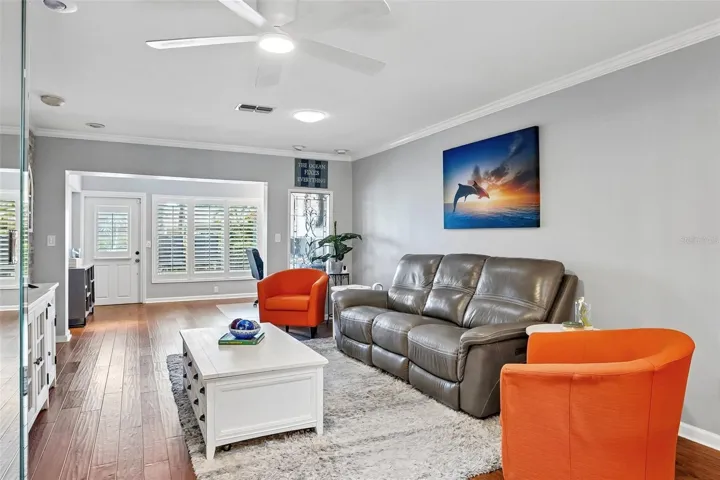 Living room dining room with beautiful engineered hardwood flooring, A travertine accent wall, and LumaDome lighing extends out to sunroom / flex space.