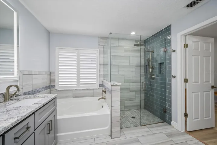 Remodeled primary bath with soaking tub and frameless glass shower