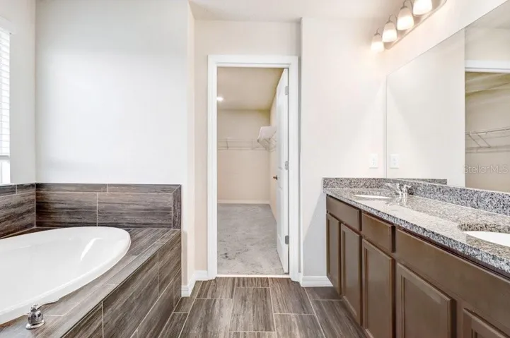 Primary Bathroom with soaking tub, walk in shower, duel sink vanity and beautiful wood plank tiles