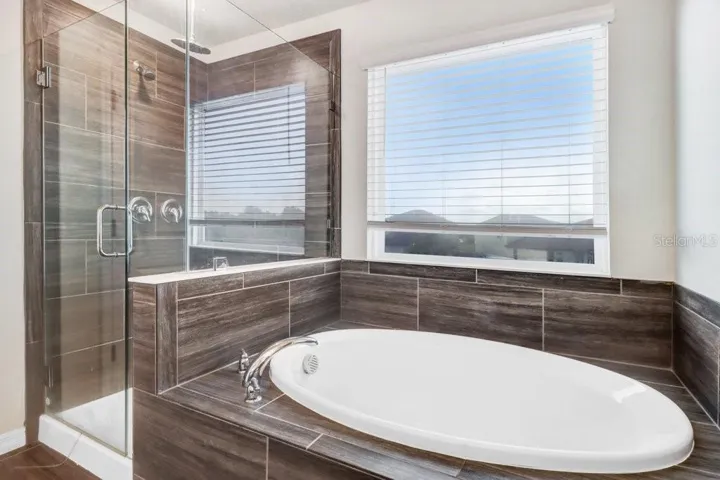 Primary Bathroom with soaking tub,  walk in shower, duel sink vanity and beautiful wood plank tiles